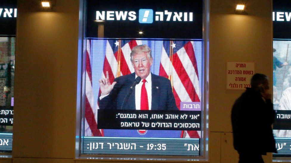 A man walks past a screen in Tel Aviv, Israel, showing the inauguration of Donald Trump on 20 January 2017
