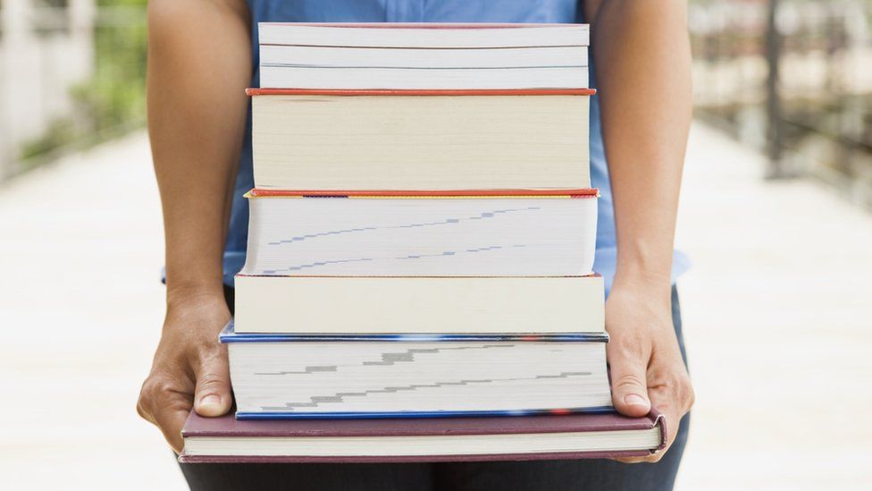 Person carrying a stack of books