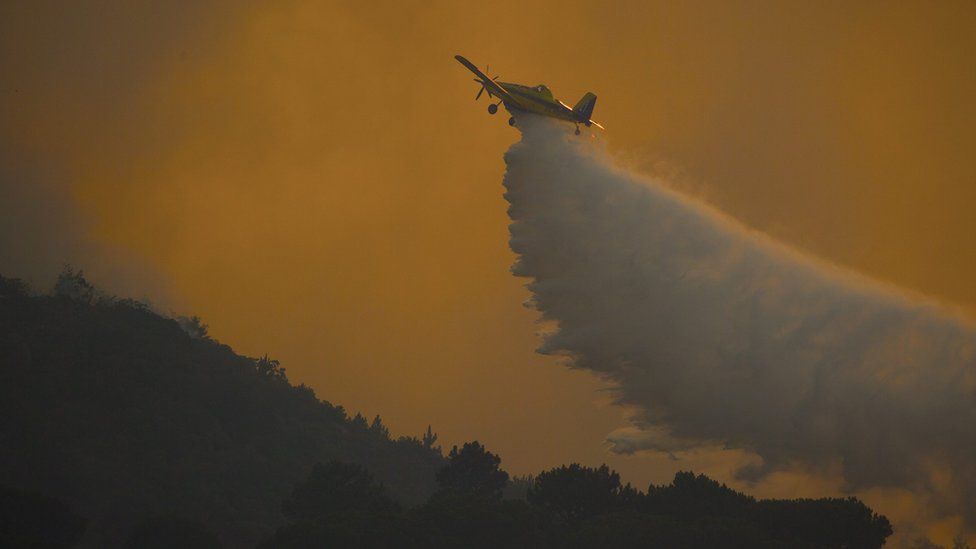 An aircraft drops water on a wild fire raging in the Helderberg mountains in South Africa