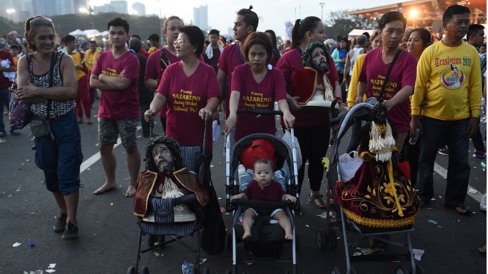 Filipino families push prams, one of which contains a child and two others replicas of the statue. Manila, Philippines. 9 January 2017.