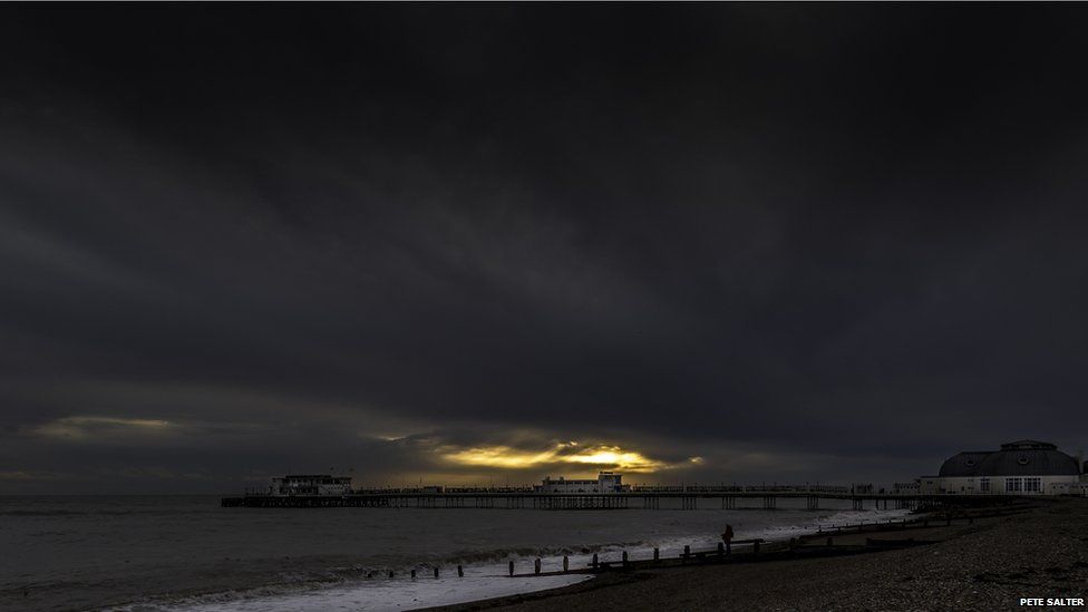 Dramatic skies at sunset by a pier