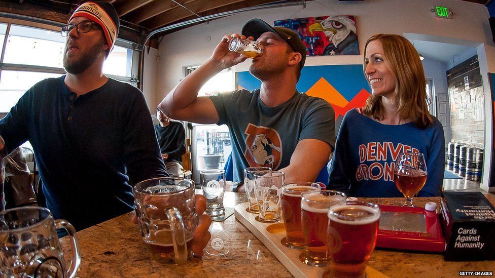 Fans drink beer while watching the Denver Broncos