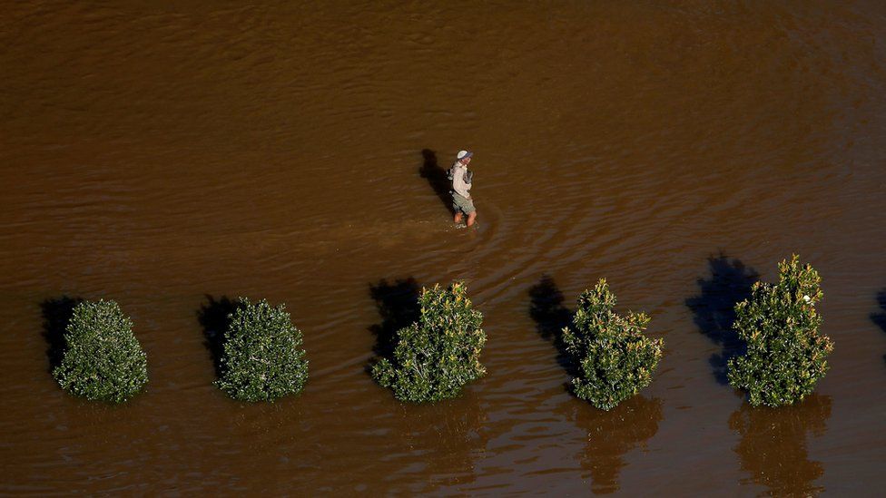 A man walks through flood waters after Hurricane Matthew in Lumberton, North Carolina October 10, 2016.