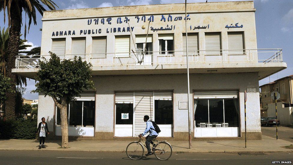 A man cycling past a library