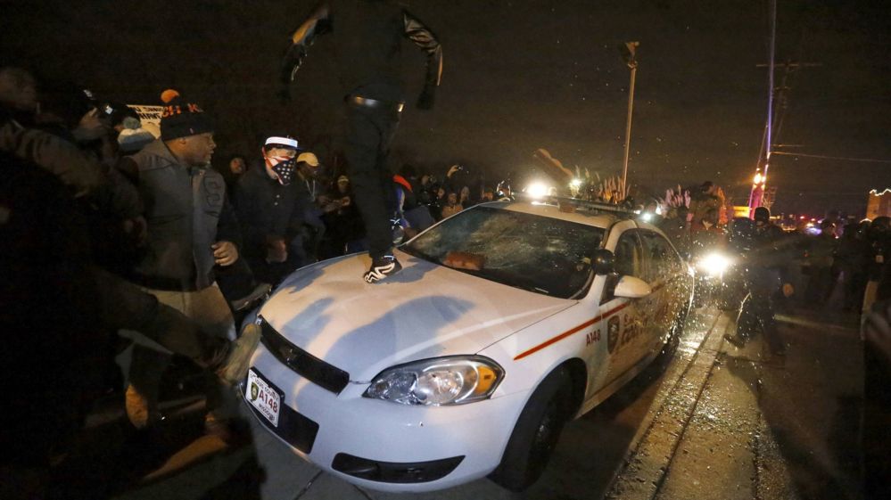 Protestors damaging a police car
