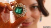 A model holding an emerald and diamond broach