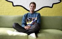 Evan Spiegel sits under the Snapchat logo