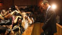 Photographers take photos of Olympic athlete Oscar Pistorius as he stands in the dock during his bail hearing at the magistrates court in Pretoria, South Africa, Friday, 22 February 2013
