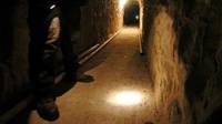 Un policia federal brilla una luz con su linterna en un tunel subterráneo en la frontera entre Mexico y EE.UU