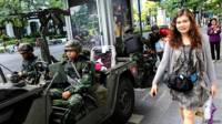 Una mujer camina junto a soldados en las calles de Bangkok