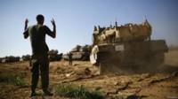Soldado israelí dirige el movimiento de un tanque en Gaza