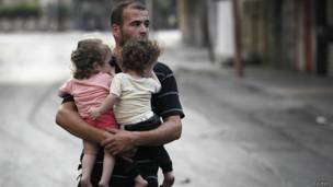 Homem carrega seus filhos em Gaza (Reuters)