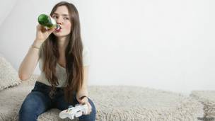 Девушка пьет пиво и играет в видеоигру