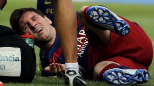 Messi tirado en el suelo mientras es atendido de su lesión.