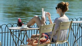 Una chica lee un libro en una terraza