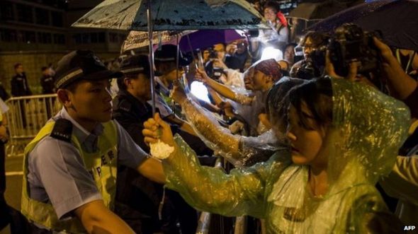 متظاهرة تحمل مظلة لرجل شرطة