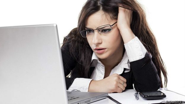 Una mujer mirando una laptop con cara de desesperación