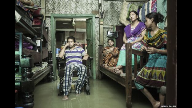 Una familia ve televisión en Chittagong, Bangladesh, a la espera de que la inundación de la marea retroceda. Las mareas son cada vez más frecuentes, afectan a los hogares y negocios como muestra la imagen de Jashim Salam.
