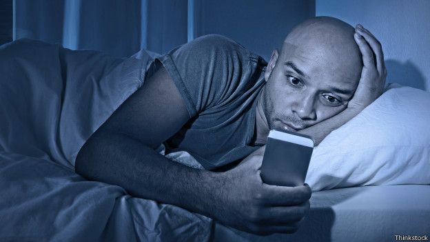 Man using cell phone in bed 