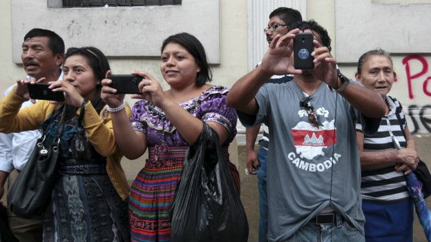 Ciudadanos toman fotografías en la calle del nuevo presidente de Guatemala