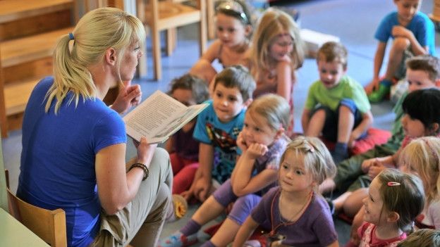 Una maestra leyéndole a unos niños