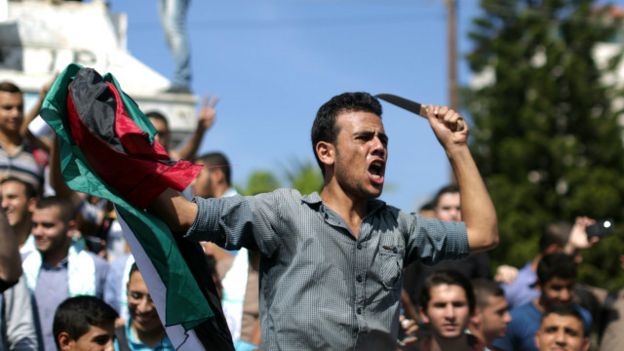 فلسطيني يرفع سكيناً