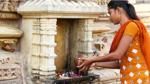 Una mujer hace una ofrenda en el templo