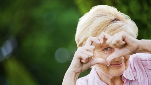 Una mujer mayor haciendo un símbolo de corazón con la mano