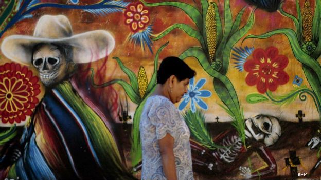 Una mujer pasa frente a un mural por Día de Muertos en Tixtla, Guerrero