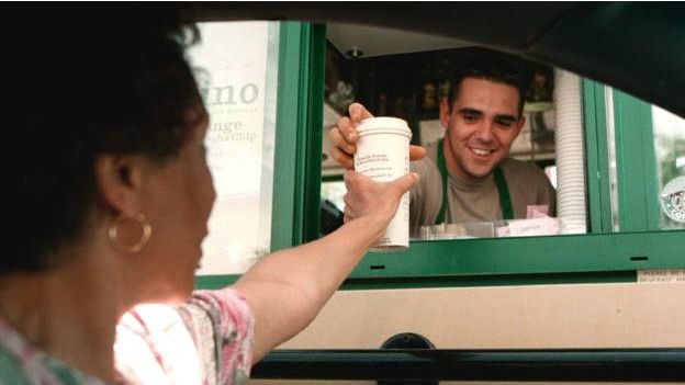 Una persona dándole una taza de café a otra