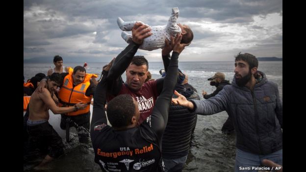 Un voluntario ayuda a un grupo de migrantes a desembarcar en la isla de Lesbos, en Grecia. 