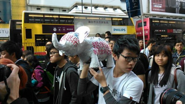 游行人士拿着大白象雕塑，讽刺政府投资“大白象”基建工程