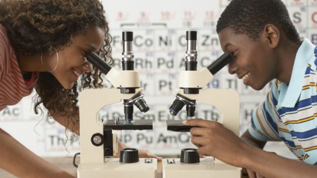 Dos jóvenes usando microscopios