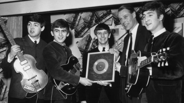 George Martin y los Beatles en una imagen de 1963 con un disco de platino.