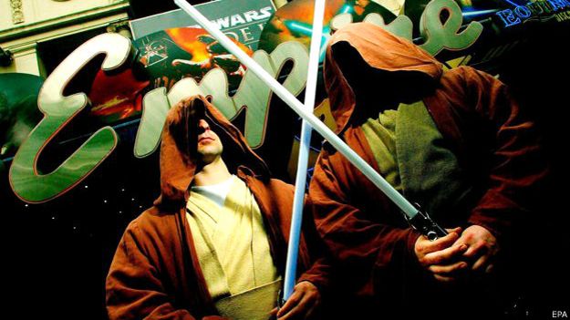 Dos hombres vestidos con la capa característica de los Jedis y portando espadas de luz