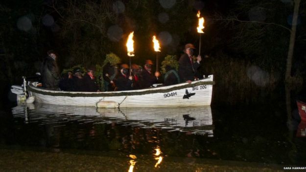 Ряженые с зажженными факелами плывут на лодке в ходе традиционного ритуала в графстве Саффолк
