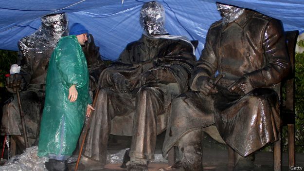 Рабочий моет памятник "Большой тройке" перед открытием