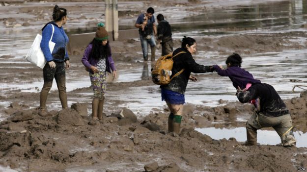 Un grupo de gente cruza una calle inundada