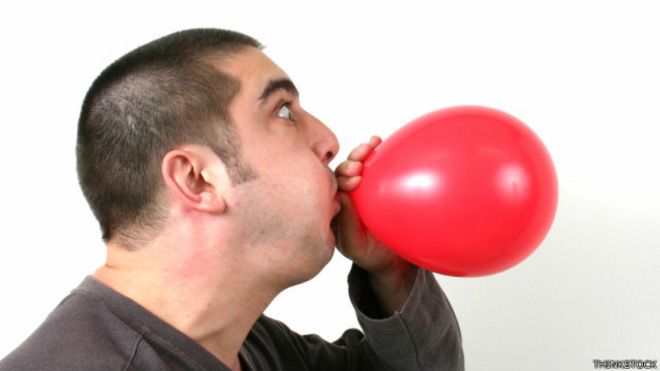 Una persona inflando un globo