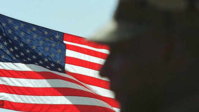 La silueta de un soldado frente a una bandera estadounidense