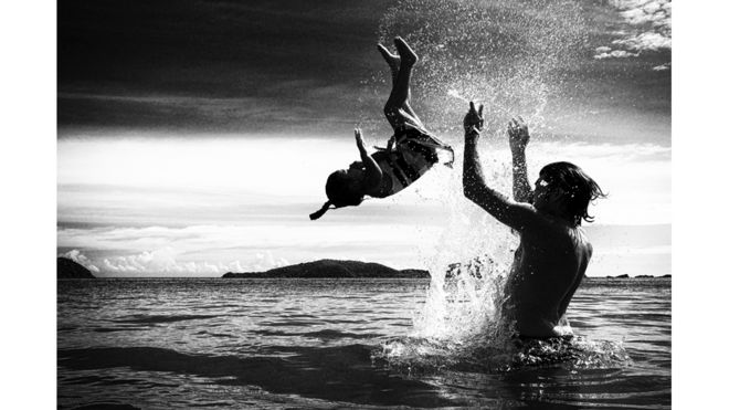 أب يلاعب ابنته في شاطئ البحر بتايلاند