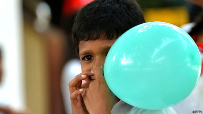 Niño inflando un globo