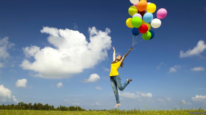 Mujer saltando con globos en la mano.