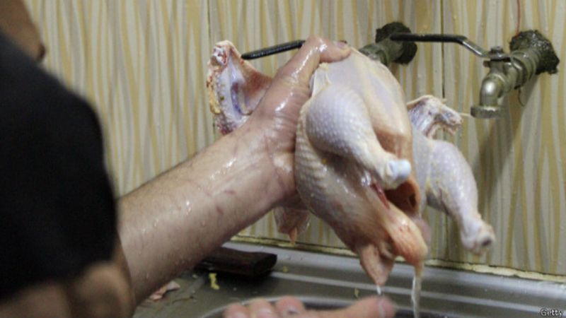 Un hombre lavando un pollo