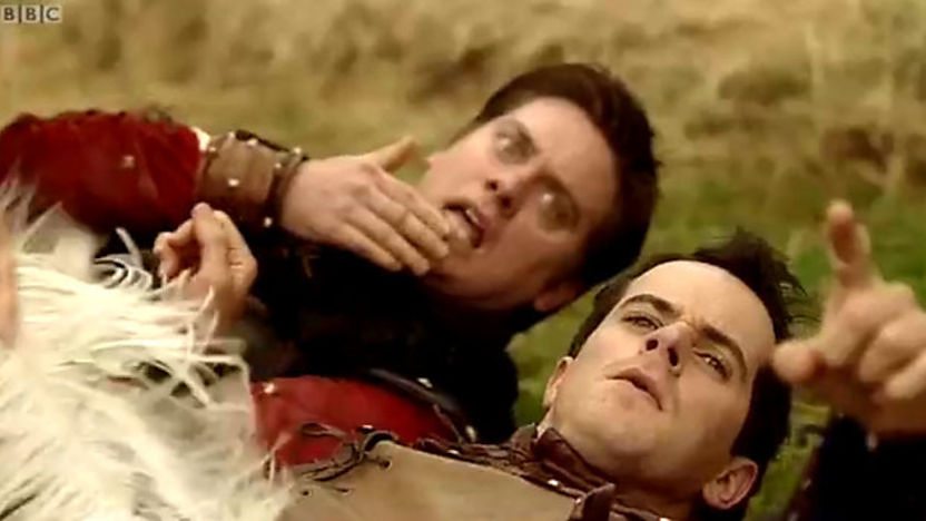Dick and Dom laying on the ground pointing at the camera.