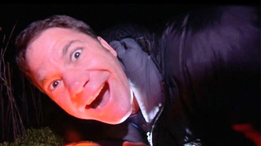 Steve Backshall pointing a torch at his face