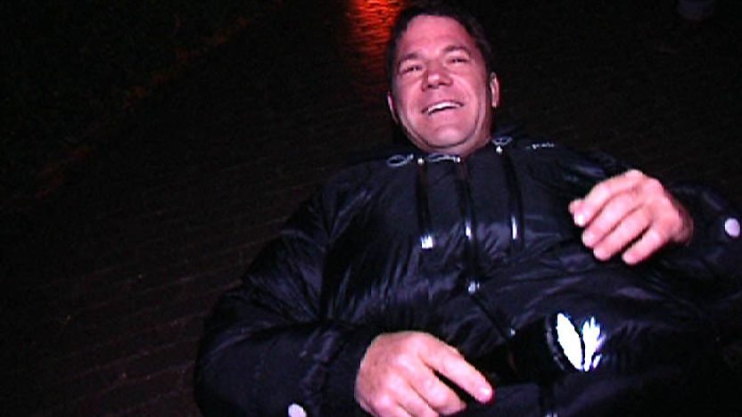 Steve Backshall lying on the ground at night with a torch