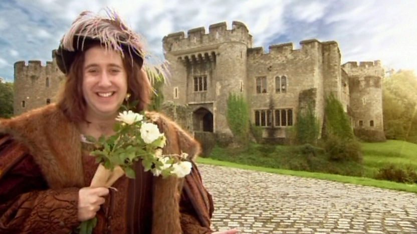 Richard III holds some flowers outside a castle
