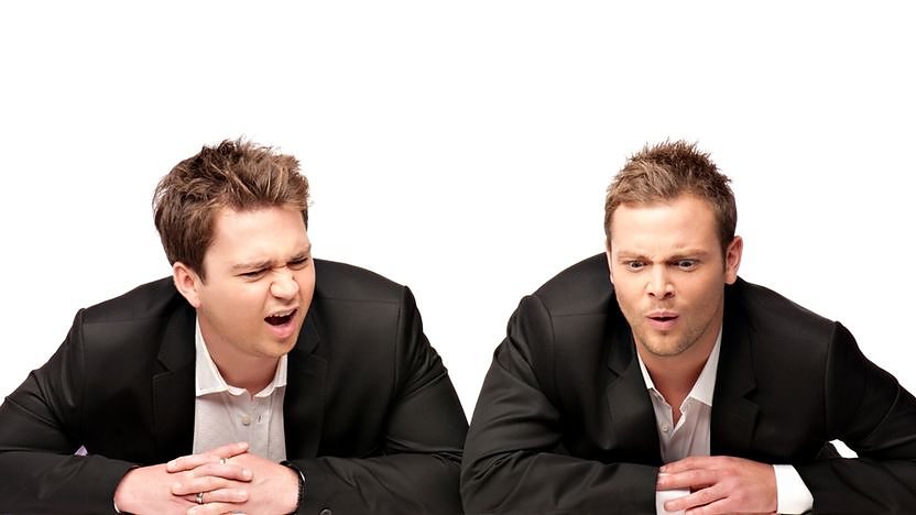 Sam and Mark stooping in front of logo