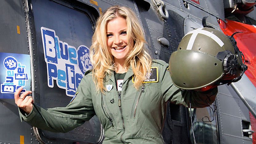 Blue Peter presenter Helen Skelton in uniform next to a Royal Navy Sea King helicopter.